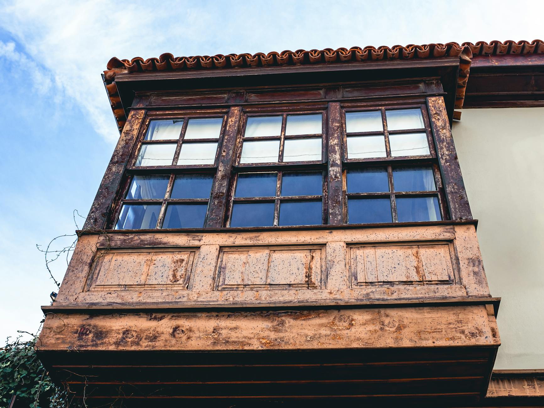 Drewniany, rustykalny balkon z oknami na tle czystego, błękitnego nieba