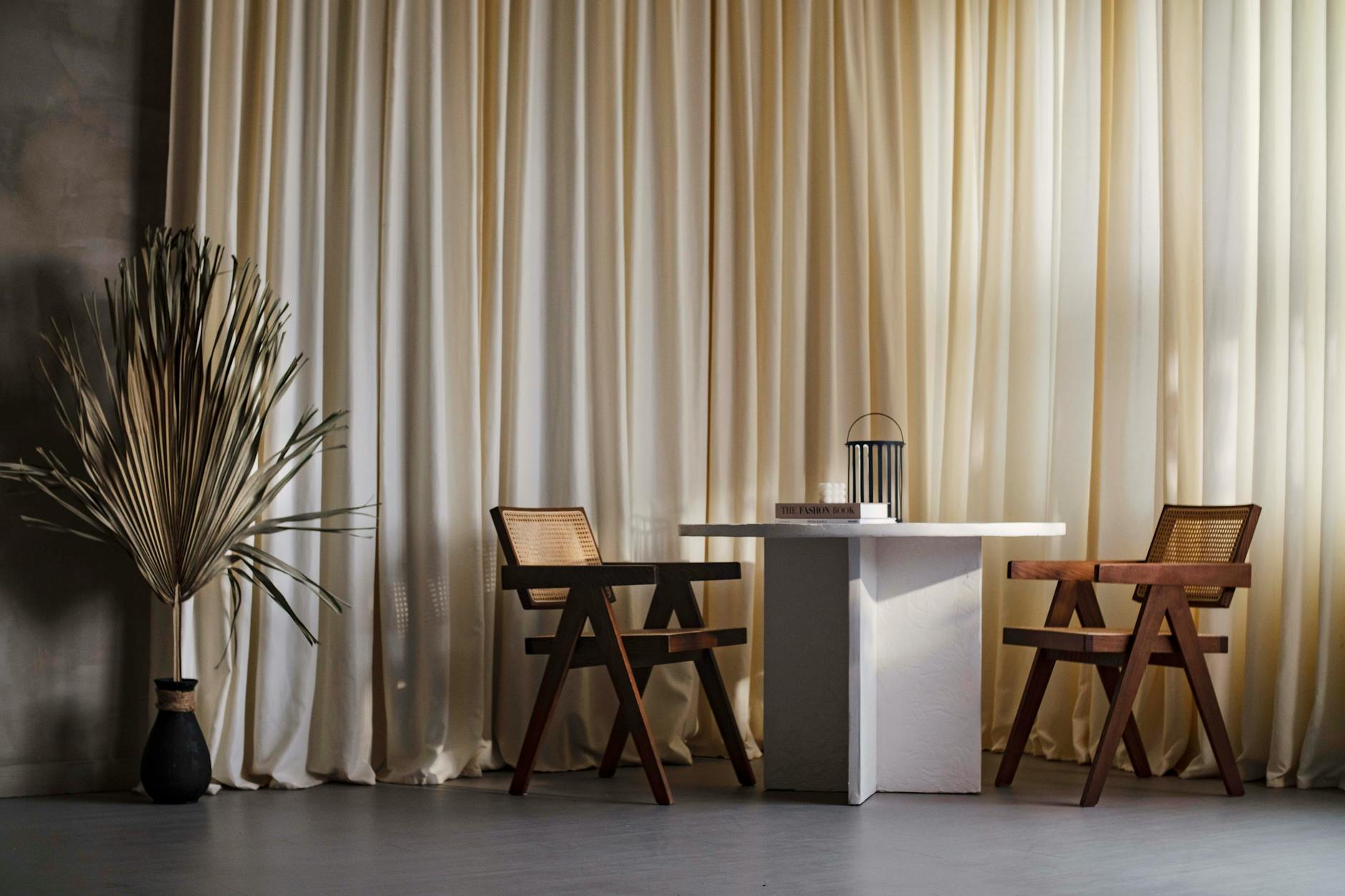 Jasne wnętrze Japandi z drewnianymi fotelami i białym stołem