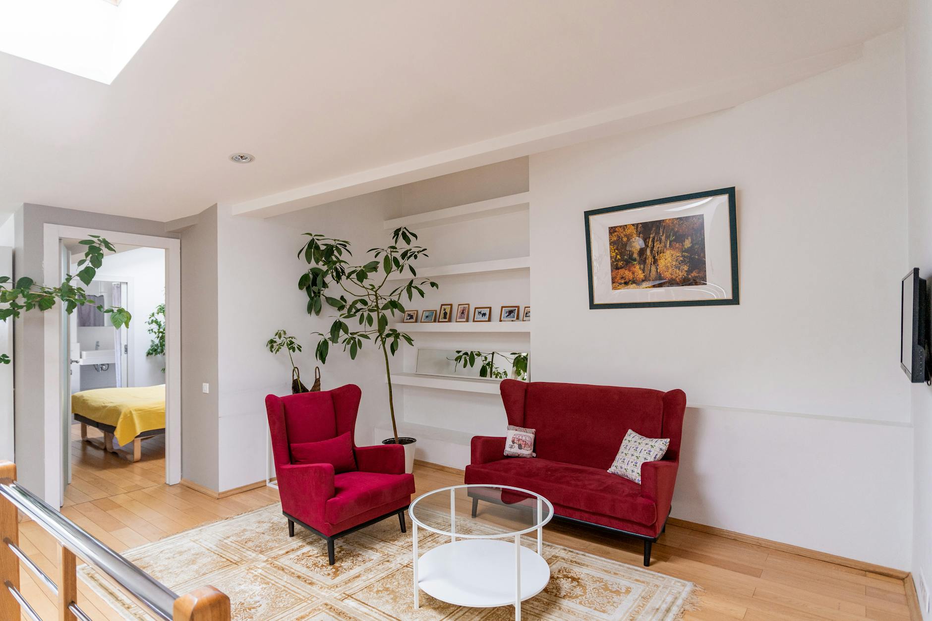 Jasny salon z czerwonymi fotelami i zielonymi roślinami jako strefa relaksu