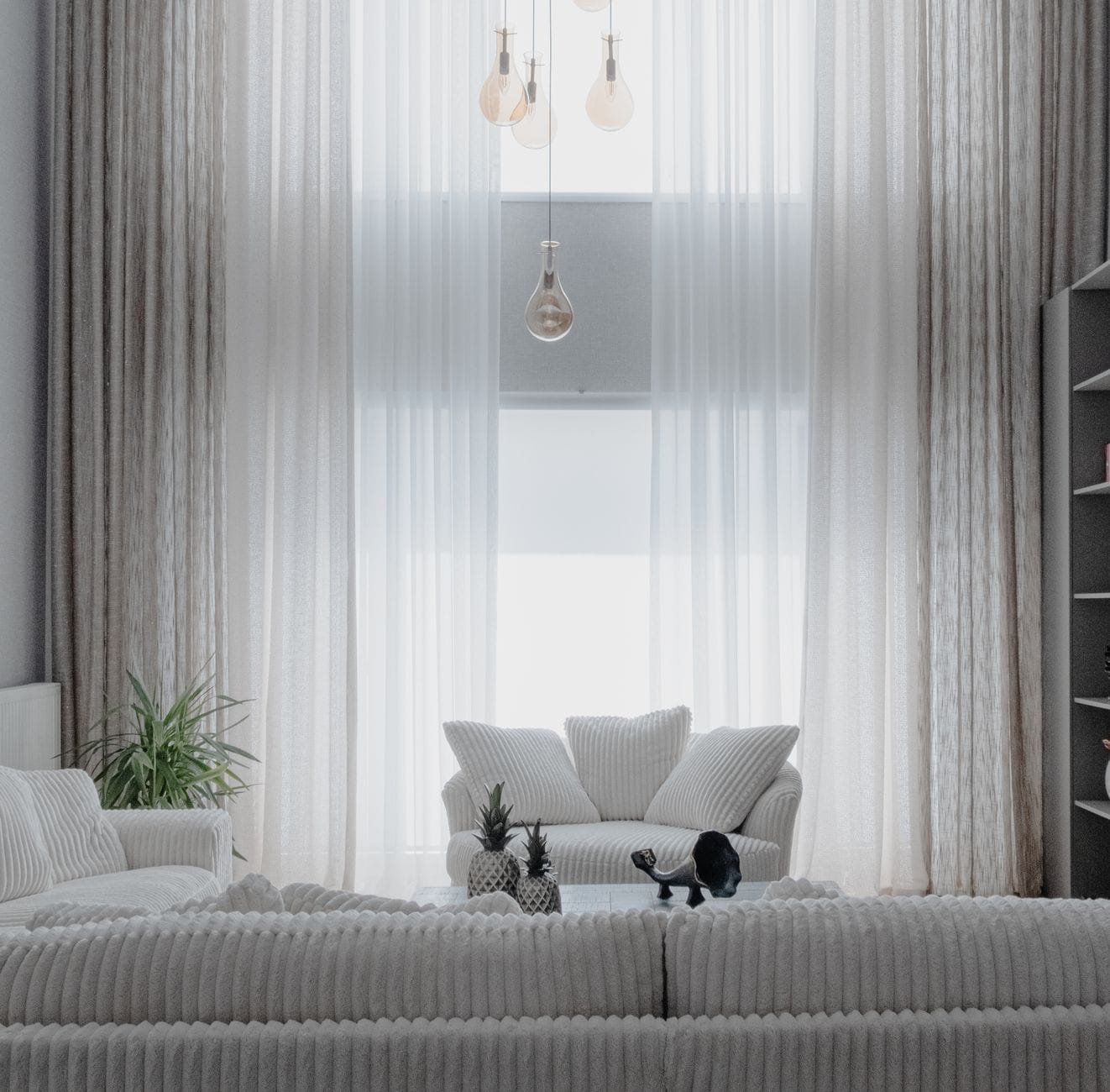 Minimalistyczny salon z białymi sofami i dużymi zasłonami